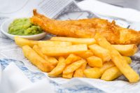 A portion of fish and chips, with fries fish, french fries, and mushy peas. Cod and Haddock are the most traditional fish for this meal.