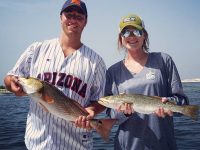 A couple holding a Redfish and a Speckled Trout which they caught in Destin Bay.