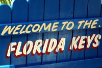 A blue fence with an inscription that reads "welcome to the Florida Keys"