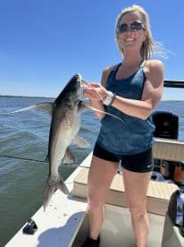 An angler proudly displaying a large catfish while fishing on a sunny day, showcasing the excitement of a successful catch.