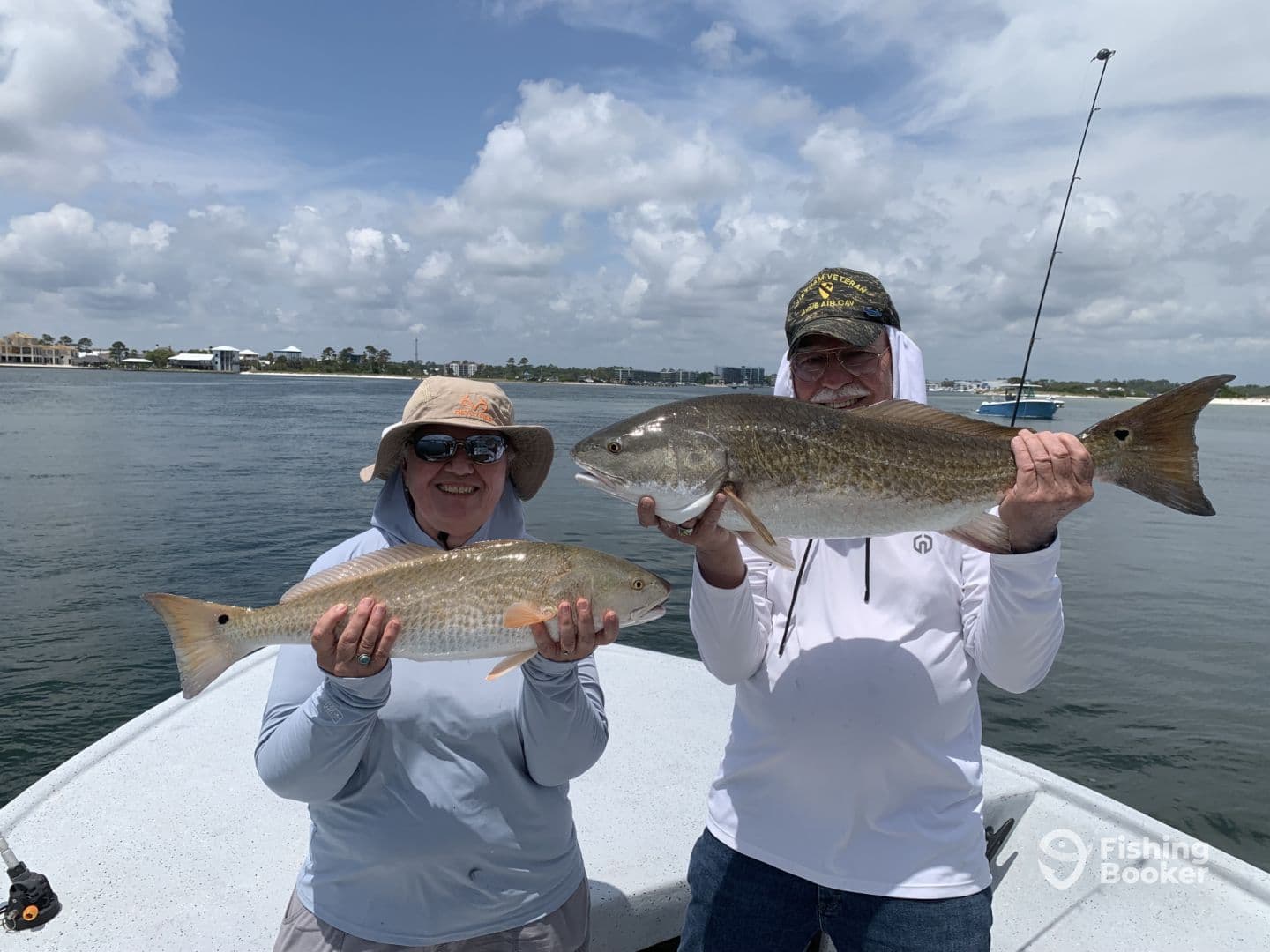 Two anglers proudly displaying their catches of Redfish while enjoying a sunny day on the water.