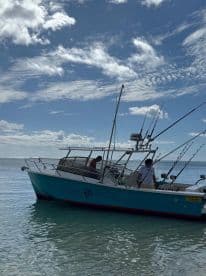 A fishing boat named 'Fishing Master' anchored in calm waters, showcasing its fishing gear and a clear blue sky.