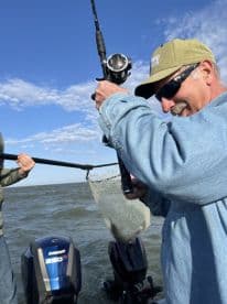 Angler reeling in a catch while fishing on a boat, showcasing the excitement of the fishing experience.