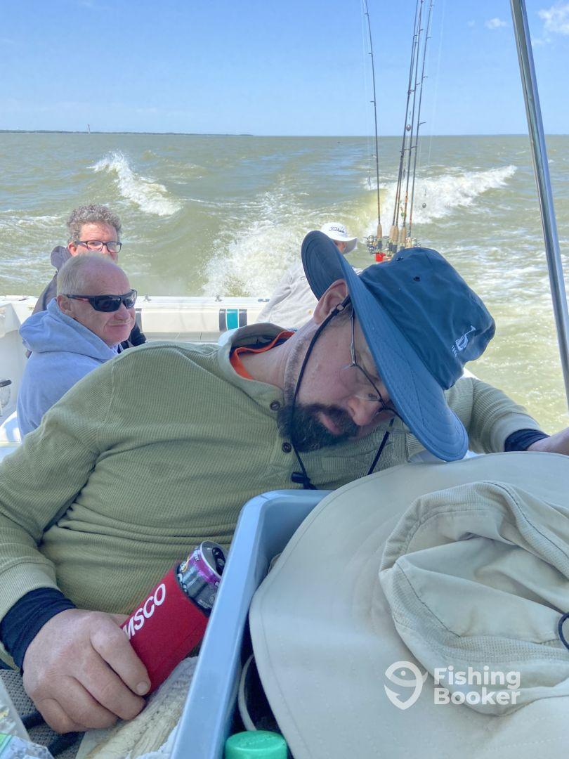 A group of anglers relaxing inside the boat, with one person resting while others enjoy the ride on a fishing trip.