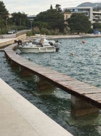 A small motorboat docked at a wooden pier, surrounded by calm waters, showcasing a scenic coastal environment.