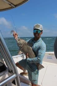 An angler proudly displaying a large fish while on a boat, showcasing a successful fishing trip in open waters.