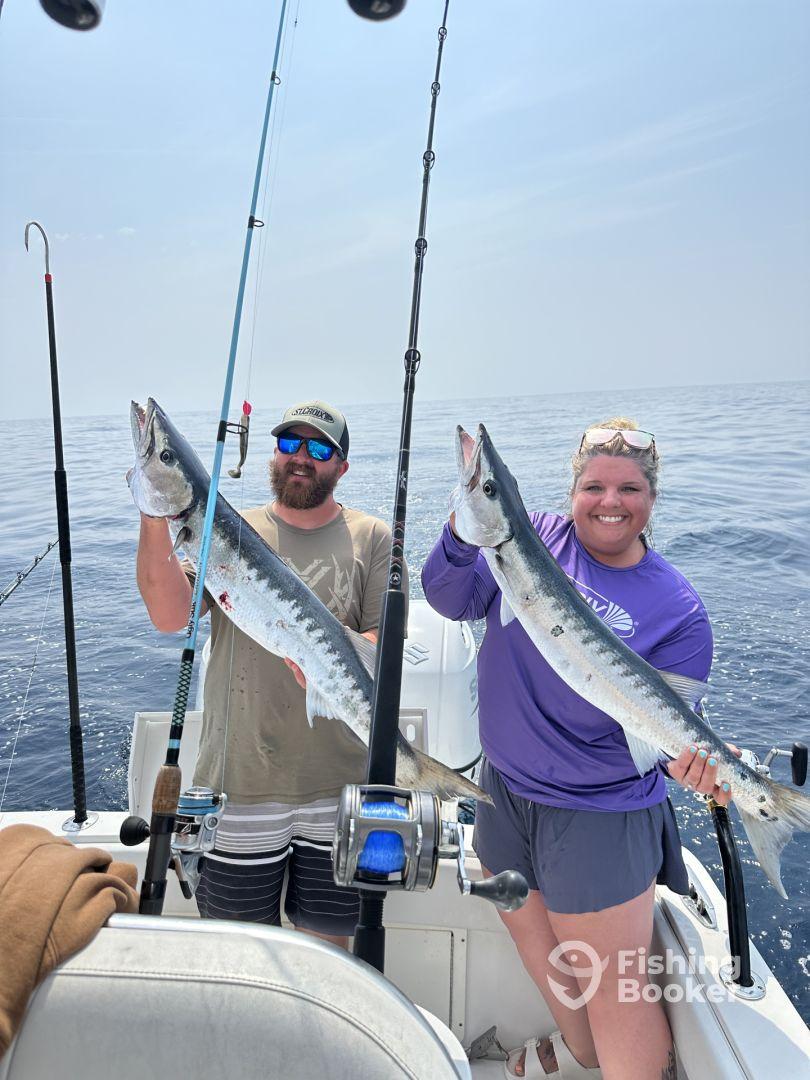 Two anglers proudly displaying their catch of Barracuda while fishing offshore, showcasing a successful day on the water.