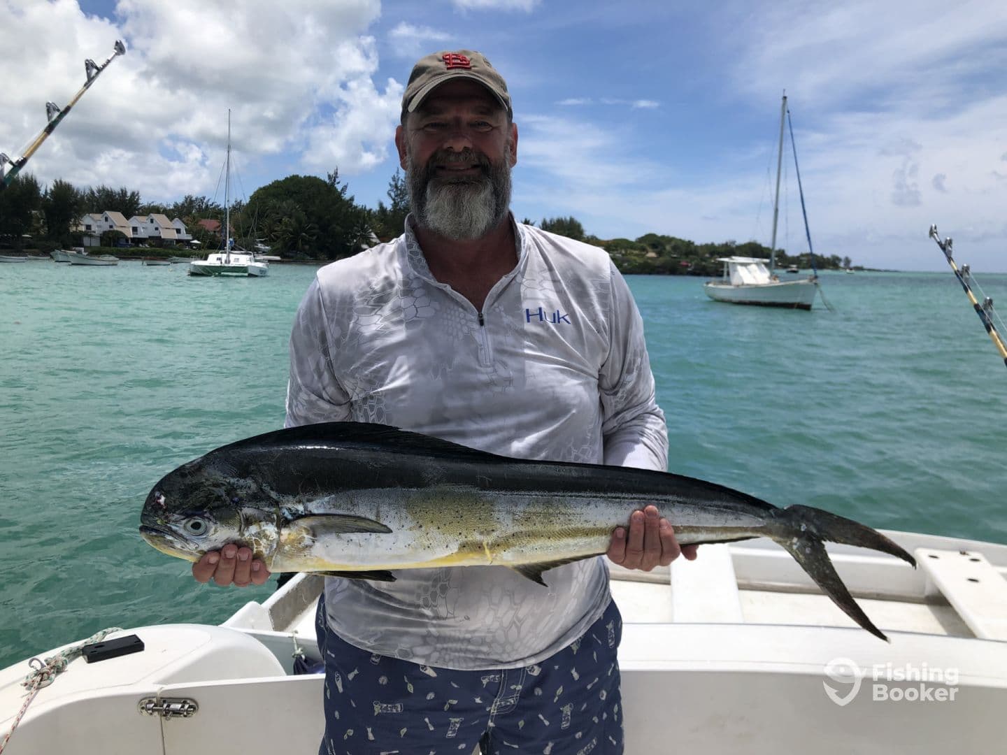 An angler proudly displaying a large Mahi Mahi while on a fishing charter in tropical waters.
