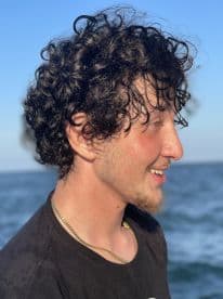 A young man enjoying a day on the water, with the ocean in the background.