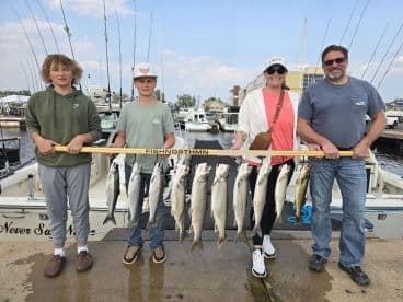 A family proudly displaying their catch of multiple fish, including trout, on a fishing trip at the marina.