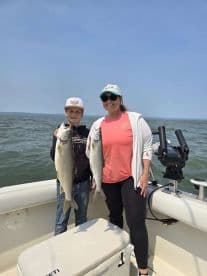A young angler and an adult proudly displaying their catch of two large Lake Trout while enjoying a day on the water.