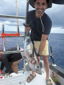 An angler proudly displaying a large Tuna while fishing offshore, showcasing a vibrant ocean backdrop.