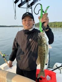 Angler proudly displaying a large Largemouth Bass while fishing on a calm lake, showcasing the excitement of a successful catch.