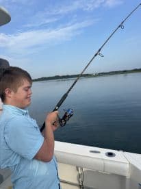 A young angler is actively fishing from a boat, enjoying a calm day on the water.