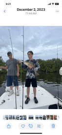A young angler proudly displaying a large Snook while fishing with an adult companion in a mangrove setting.