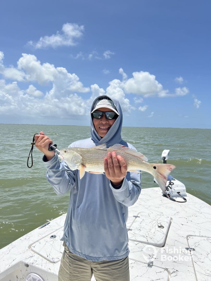 Angler proudly displaying a Redfish while fishing on a sunny day in coastal waters.