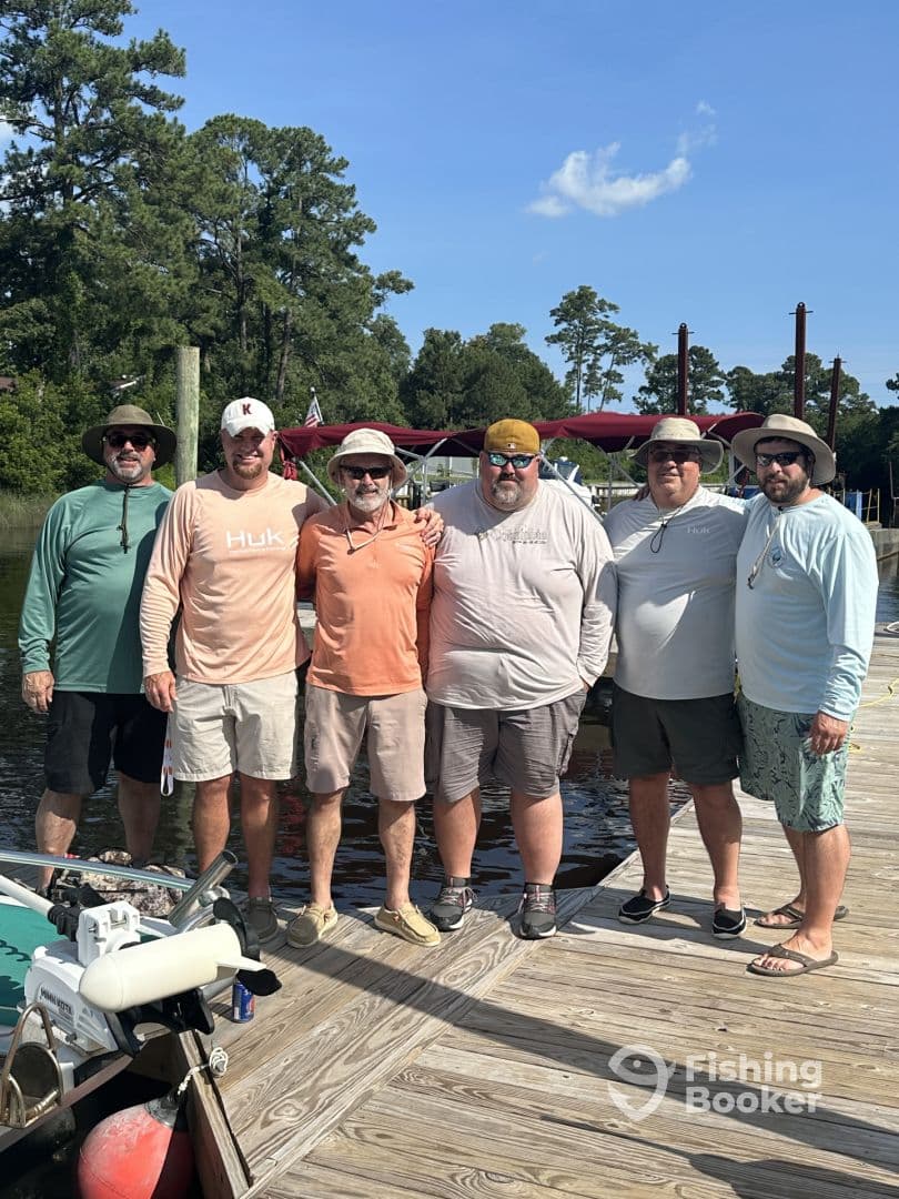 Group of anglers posing together on the dock, showcasing camaraderie after a fishing trip.
