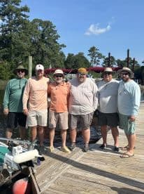 Group of anglers posing together on the dock, showcasing camaraderie after a fishing trip.
