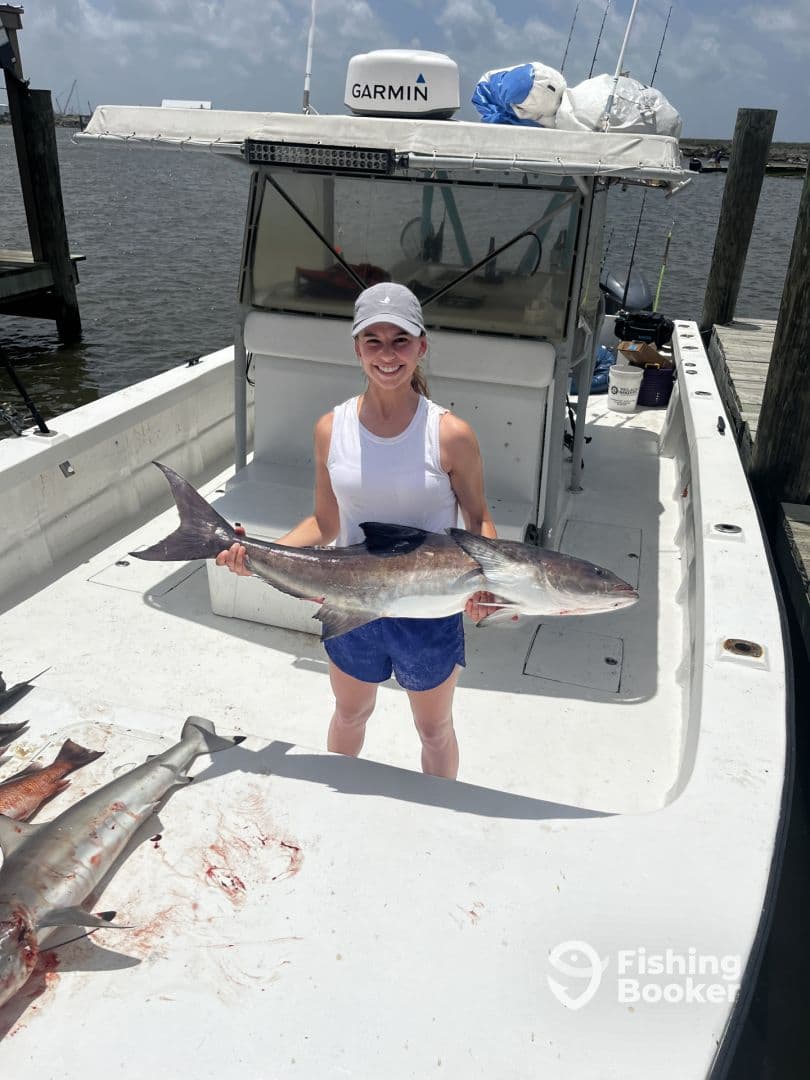 An angler proudly displaying a large shark on a fishing boat after a successful day on the water.