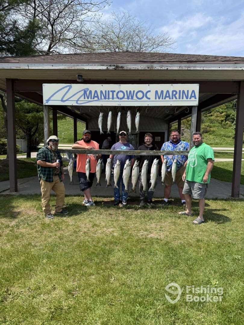 A group of anglers proudly displaying their catch of Salmon at Manitowoc Marina, showcasing a successful fishing trip.