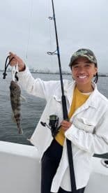 Angler smiling while holding a caught fish on a boat, showcasing a successful fishing trip.