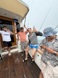 Group of friends enjoying their time on a fishing charter, showcasing a relaxed atmosphere on the boat's deck.