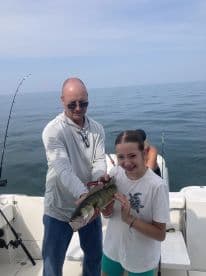 A young angler and an adult proudly displaying a large Walleye while fishing on a boat, showcasing a successful day on the water.
