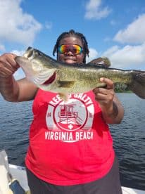 An angler proudly displaying a large Largemouth Bass while fishing on a sunny day, showcasing the excitement of a successful catch.