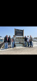 A group of anglers proudly displaying their catch of the day on a catch board at the marina, showcasing various fish species after a successful fishing trip.