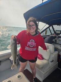 An excited angler proudly displaying a Walleye caught while fishing from a boat, showcasing a fun day on the water.