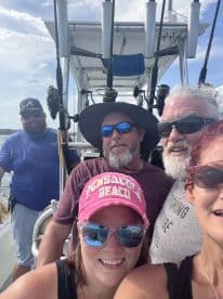 Group of anglers posing inside the boat, showcasing fishing rods and enjoying their time on the water.