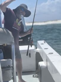 An angler reeling in a fish while on a boat, showcasing the excitement of fishing in open waters.