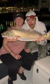 Two anglers proudly displaying a large Redfish caught during a night fishing trip.