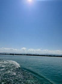 A scenic view of the boat's wake against a clear blue sky, showcasing the tranquil fishing environment.