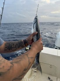 Angler holding a freshly caught fish while on a fishing charter in open waters, showcasing the thrill of the catch.