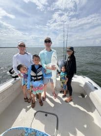 Family enjoying a successful fishing trip, showcasing a large shark caught in the open water.