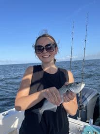 A young angler proudly displaying a caught fish while on a boat, enjoying a day of fishing on the open water.