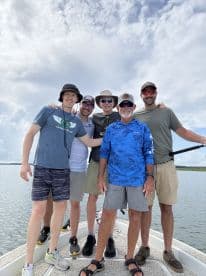 Group of five anglers posing together on a boat, enjoying a day out on the water.