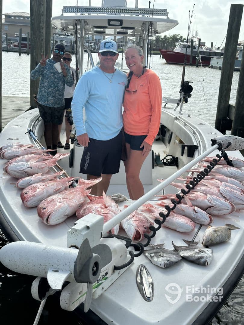 A couple proudly displaying their catch of Red Snapper on the boat after a successful fishing trip.