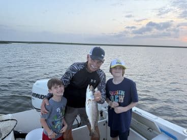 A proud moment for a family as they display a large Speckled Trout caught during their fishing trip on a scenic waterway.