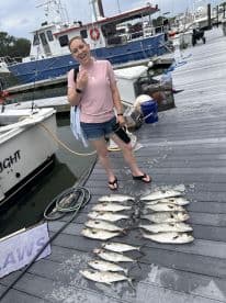 A smiling angler proudly displaying a catch of multiple fish on the dock after a successful fishing trip.