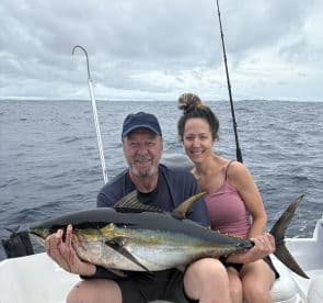 Two anglers proudly displaying a large Yellowfin Tuna while fishing offshore, showcasing a successful day on the water.
