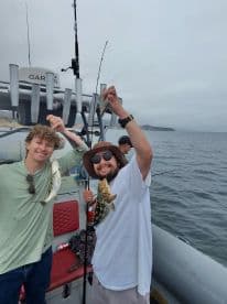 Two anglers proudly displaying their catches of bass while fishing on a boat, showcasing a fun day on the water.