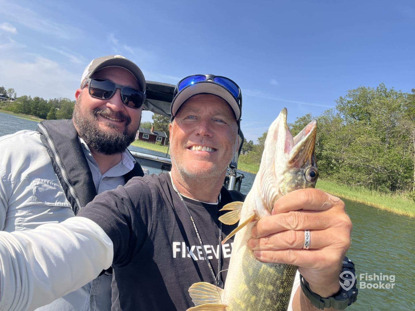 Two anglers posing with a Northern Pike while enjoying a sunny day on the water.