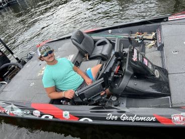 A young angler seated at the helm of a Phoenix bass boat, ready for a day of fishing on the water.