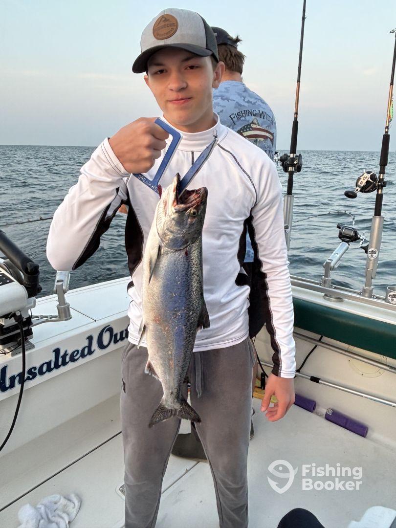 A young angler proudly displaying a large fish while fishing on a boat, showcasing the excitement of a successful catch.