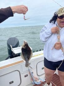 Excited angler reeling in a Flounder while fishing on a boat, showcasing the thrill of the catch.