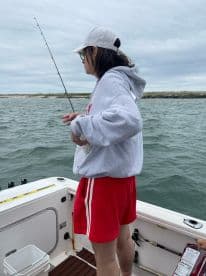 A young angler is focused on fishing from a boat, casting lines in a coastal fishing environment.