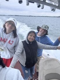 A cheerful group of anglers enjoying their time on a boat, with a scenic water backdrop, showcasing a fun fishing adventure.
