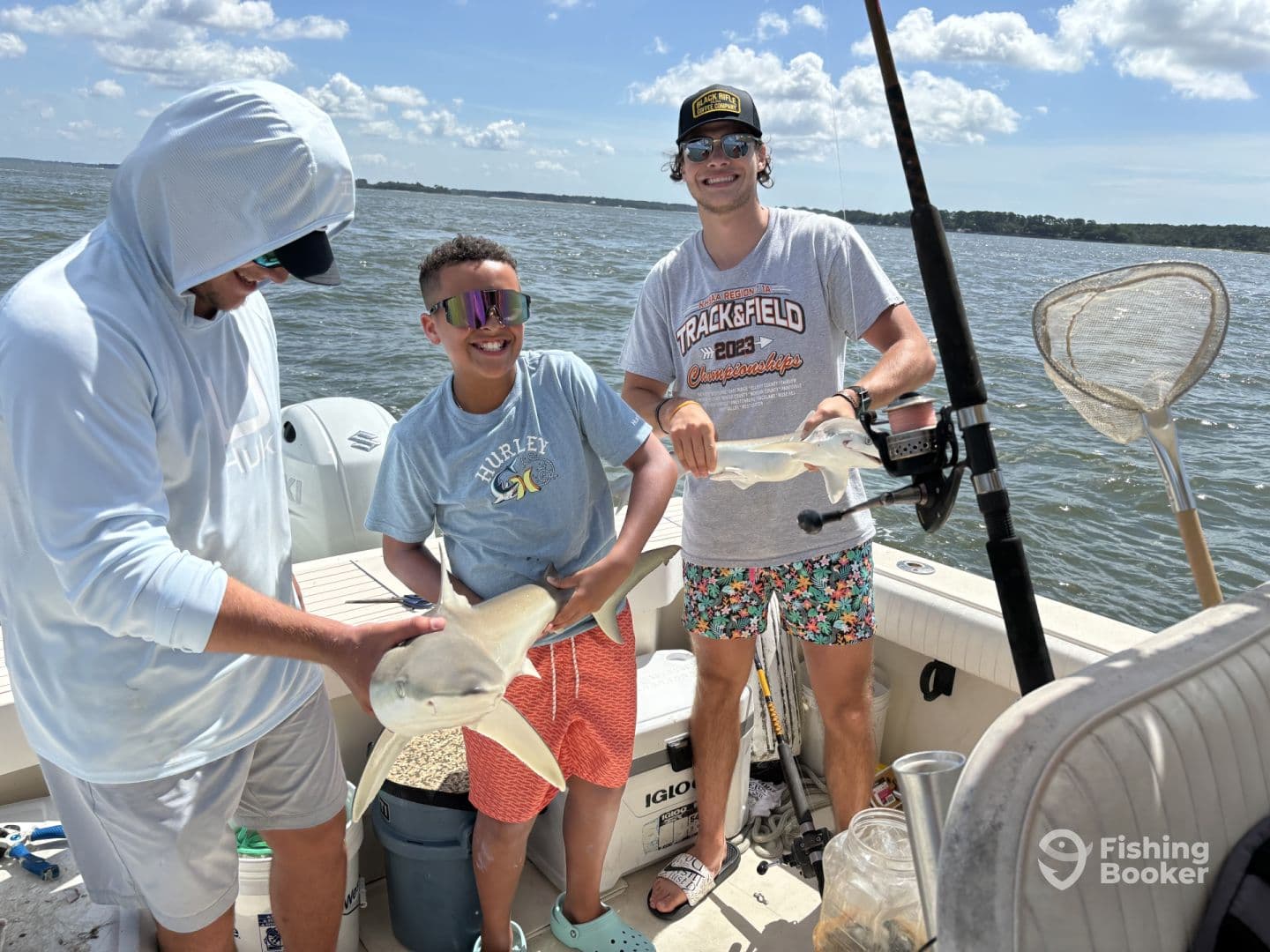 A young angler joyfully holds a fish alongside two adults on a boat, showcasing a successful fishing trip in a sunny coastal environment.